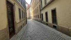 Úzká dlážděná ulička v historickém centru Prahy s barevnými domy